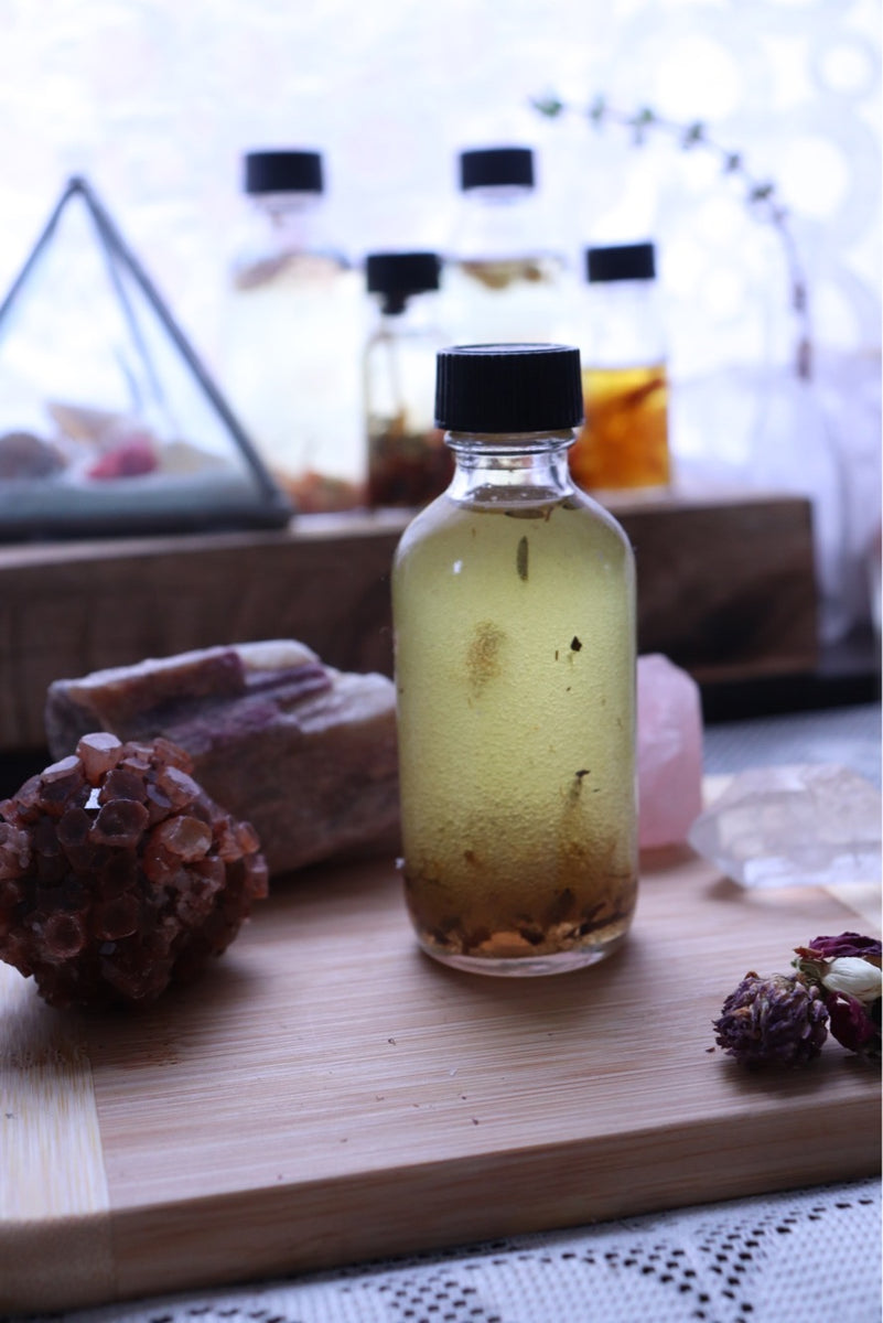 Herbal Oil Infusion surrounded by crystals. In the background are additional oils and a pyramid.